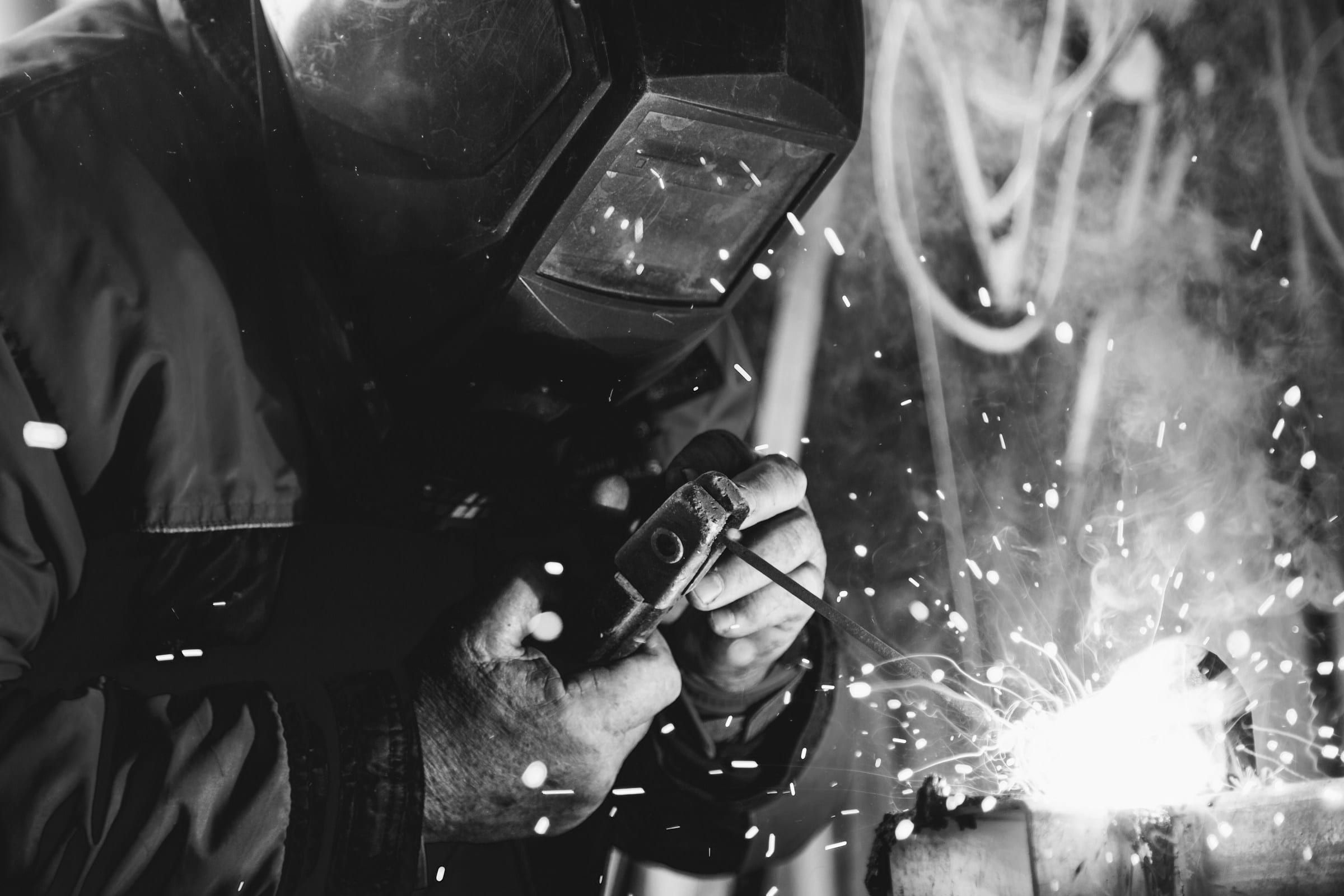 Saldatore con maschera al lavoro tra le scintille